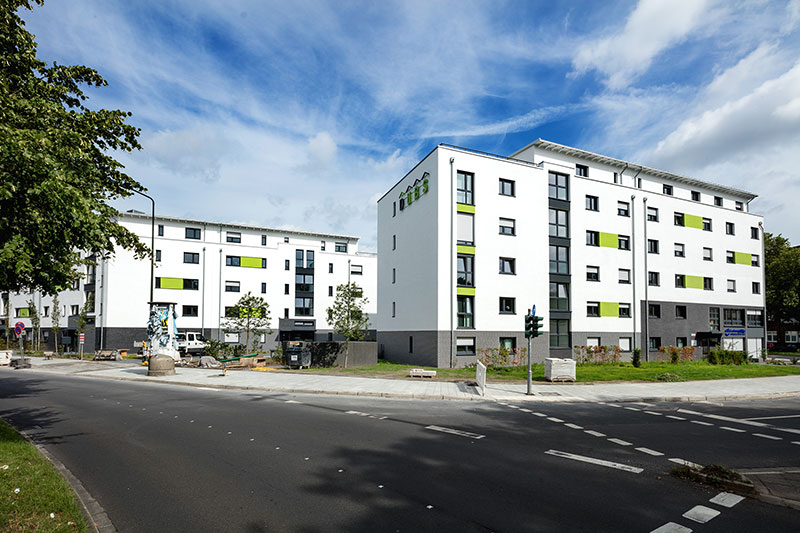 Modernes Wohnquartier mit klarer Fassadengestaltung und grünen Akzenten