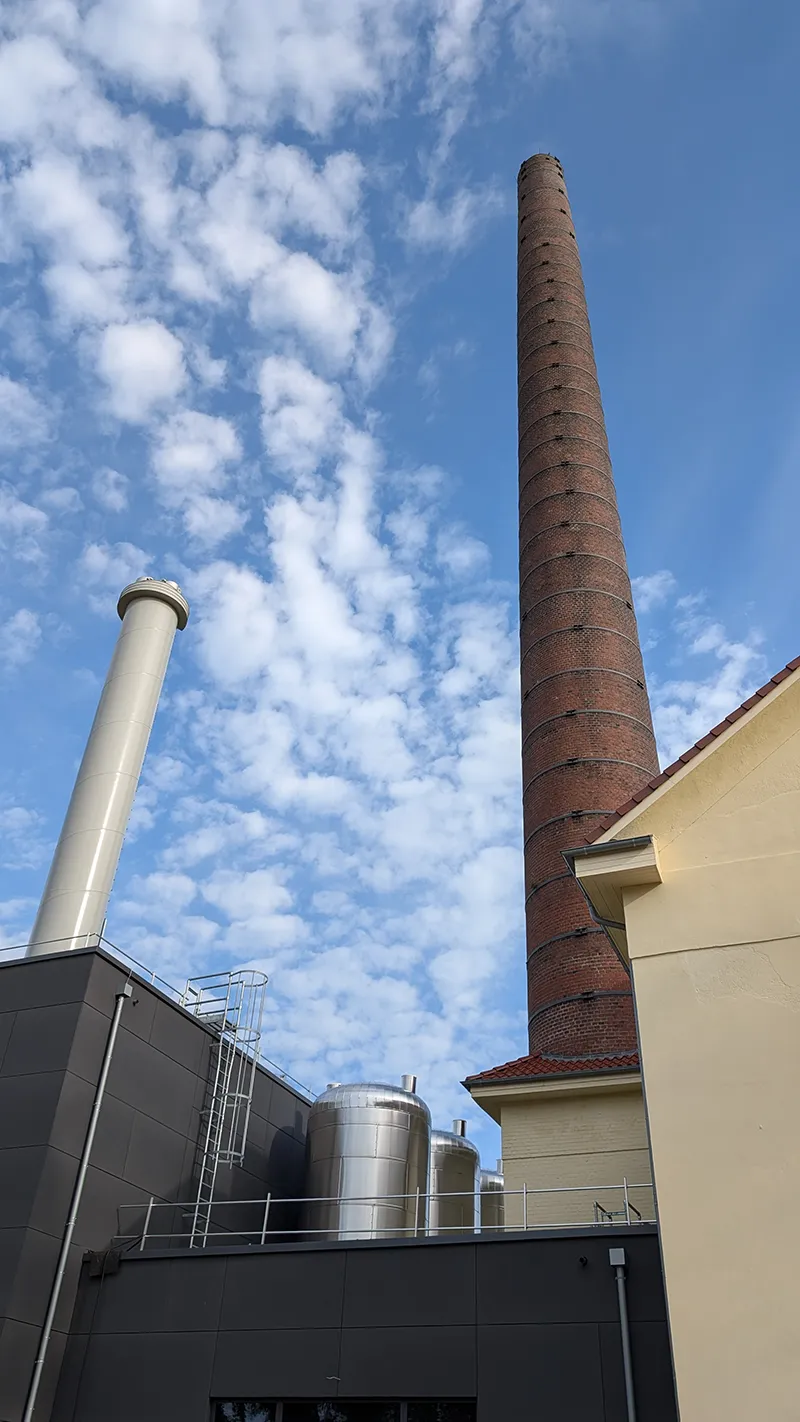Hoher Industrieschornstein mit technischer Anlage im Vordergrund