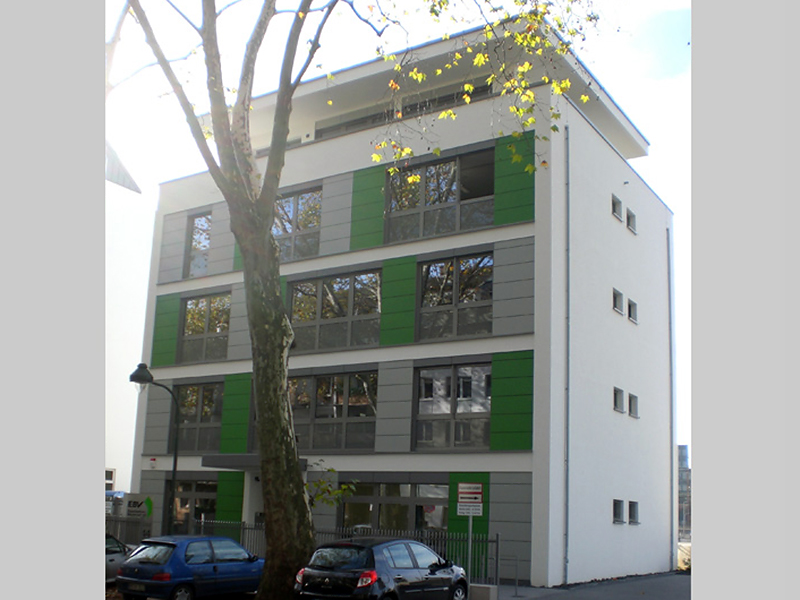 Modernes Wohngebäude mit klar gegliederter Fassade und grünen Akzenten