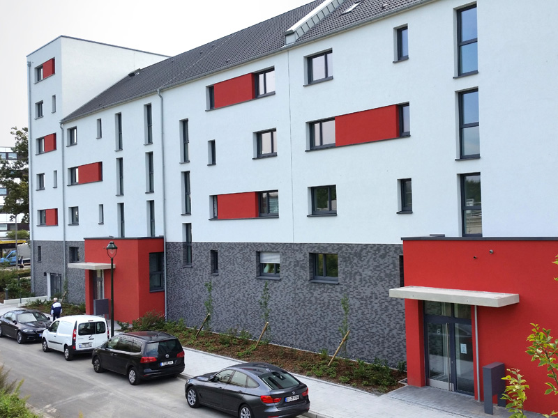 Modernes Wohngebäude mit klarer Fassadengestaltung und roten Akzenten