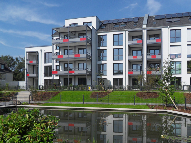 Modernes Wohngebäude mit Balkonen und Wasseranlage im Vordergrund