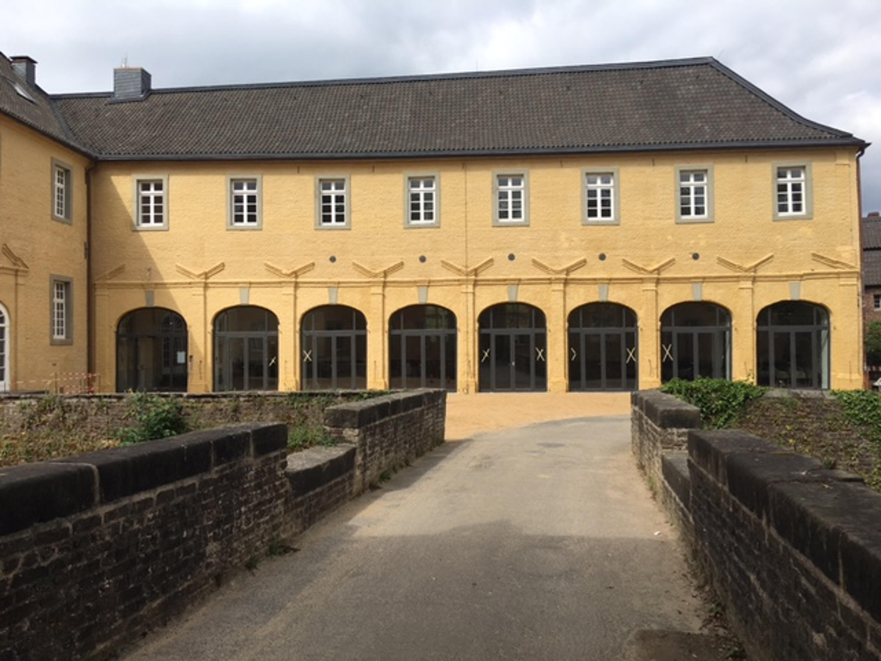 Historisches Gebäude mit Arkadenfassade und vorgelagerter Brücke