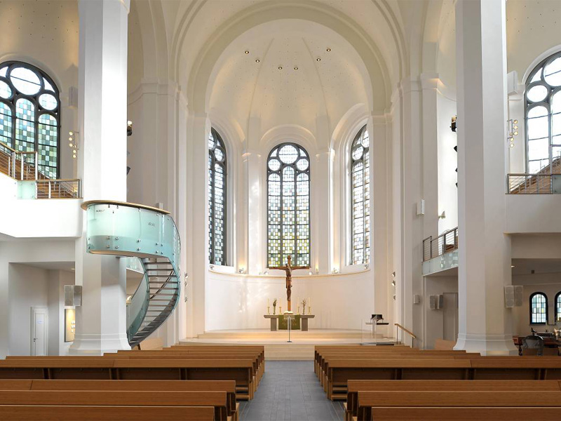 Heller Kircheninnenraum mit Altarbereich und Empore