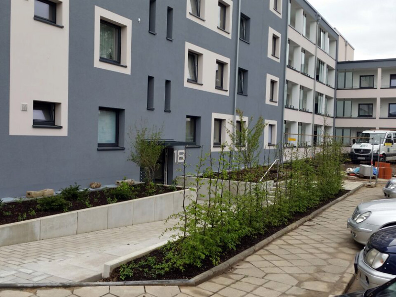 Modernes Wohngebäude mit klar strukturierter Fassade und begrüntem Eingangsbereich