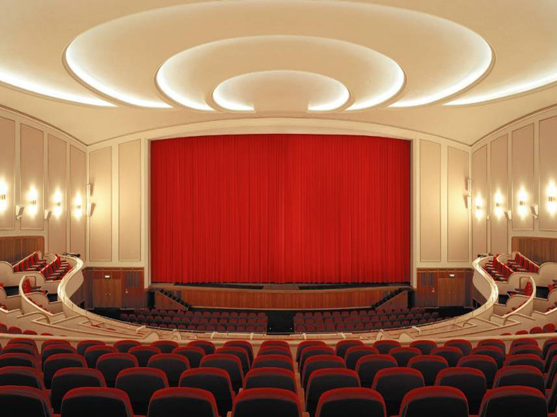 Historischer Kinosaal mit rotem Bühnenvorhang und Zuschauerreihen