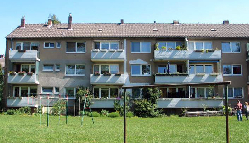 Modernes Wohngebäude mit Balkonen und vorgelagertem Grünbereich